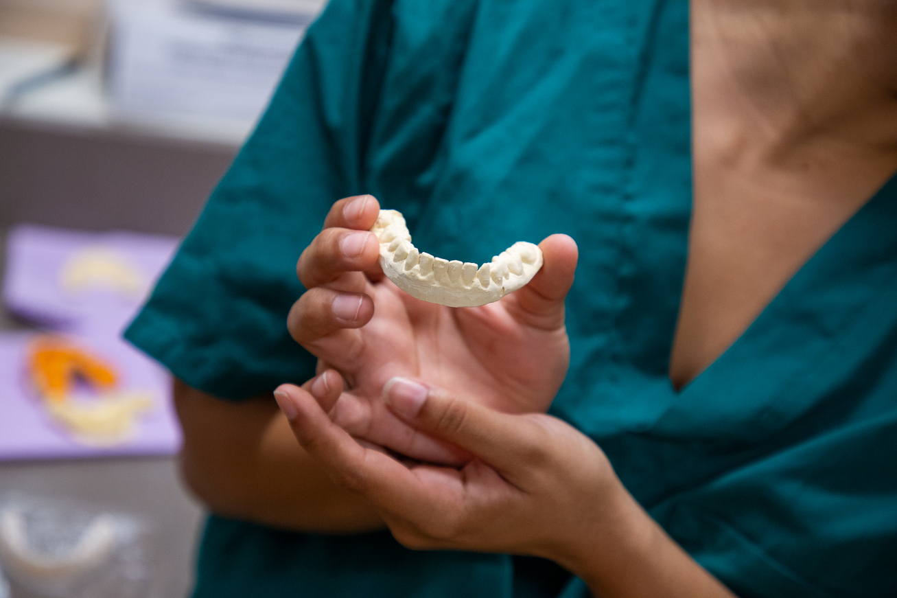 A dental student holds out a tooth mold