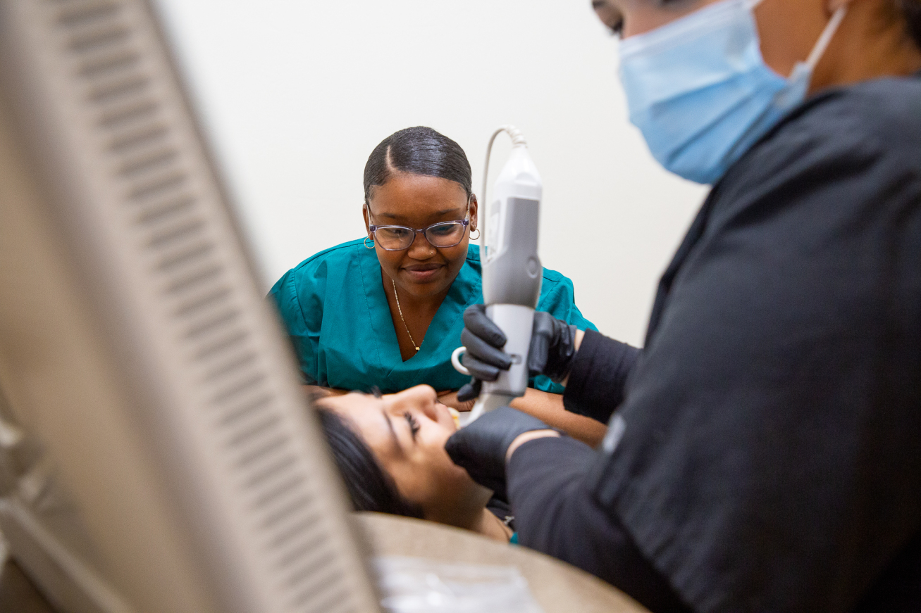 A dental tech works in a student's mouth to show fellow students how the scanner tool works