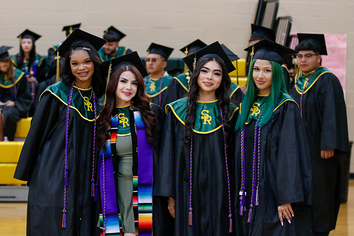 A group of girls smile for a photo in their caps and gowns