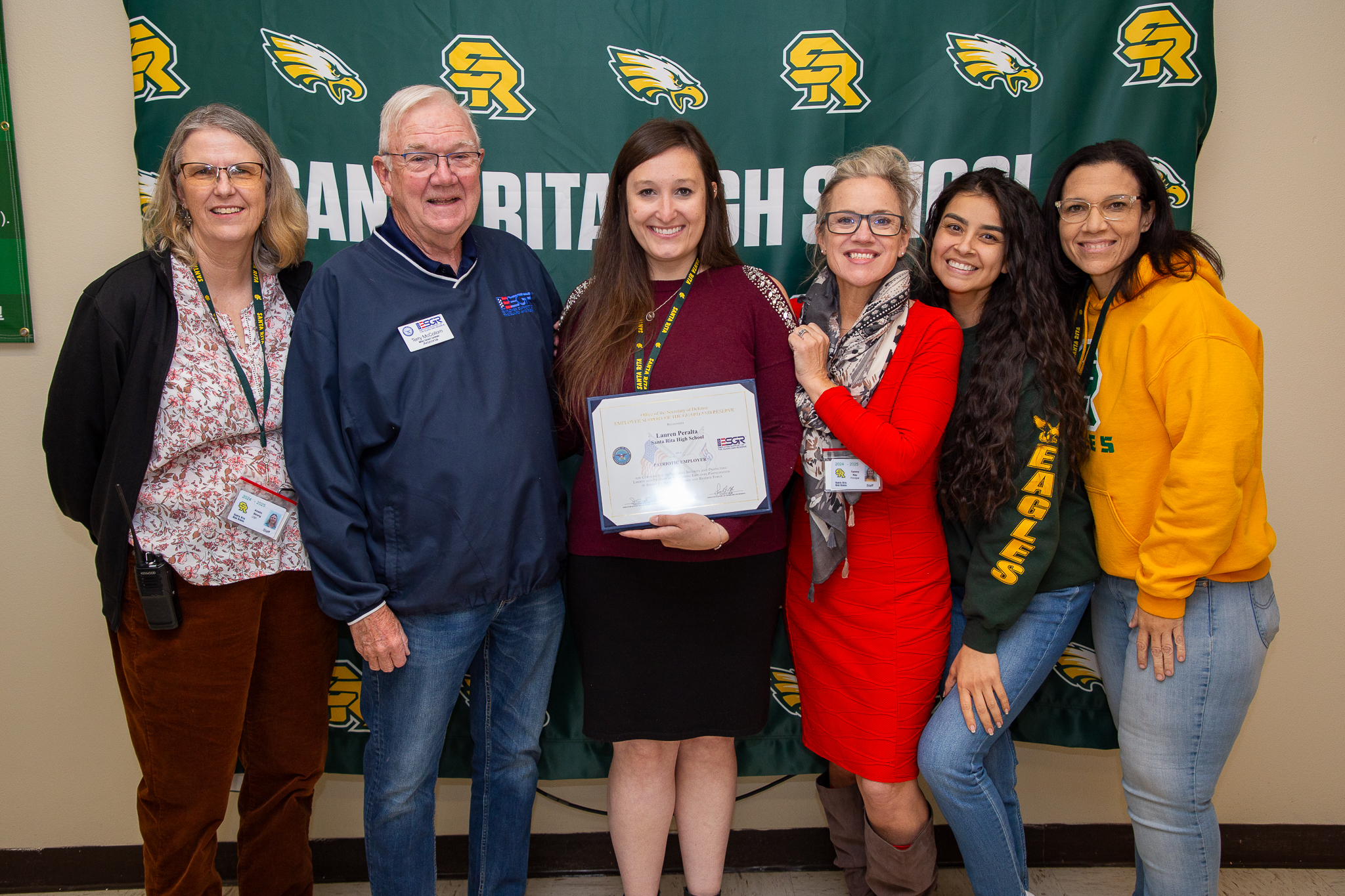 A group of people stand around a woman holding a certificate