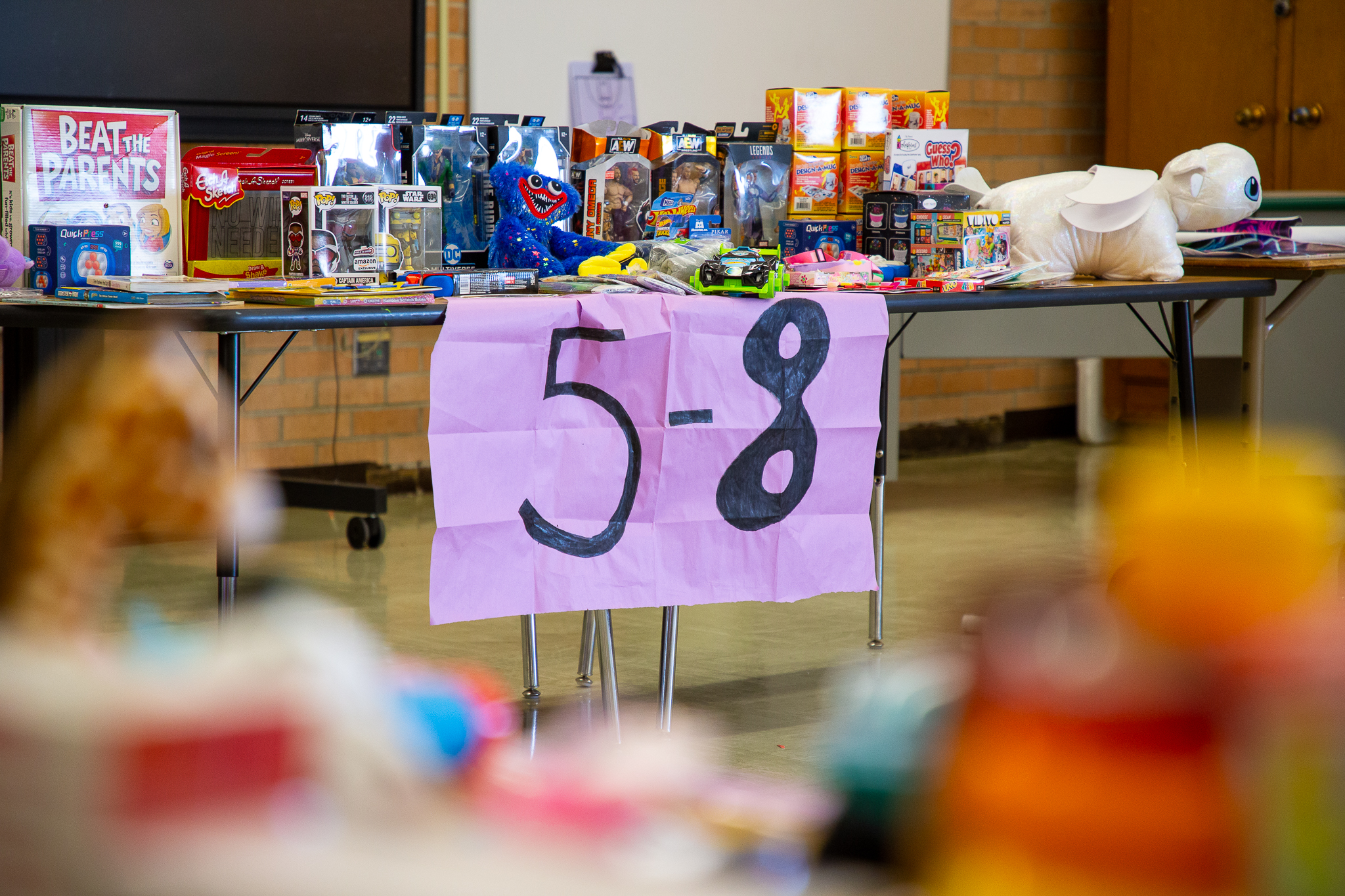 Toys sit on a table labeled with a purple 5-8 banner