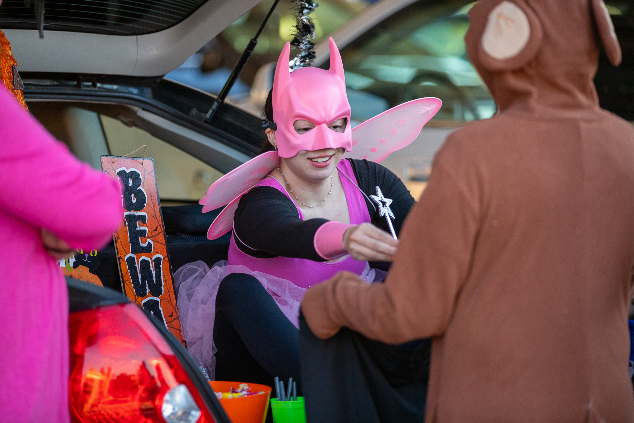 A girl in a pink fairy costume hands treats out to a kid in a monkey jumpsuit