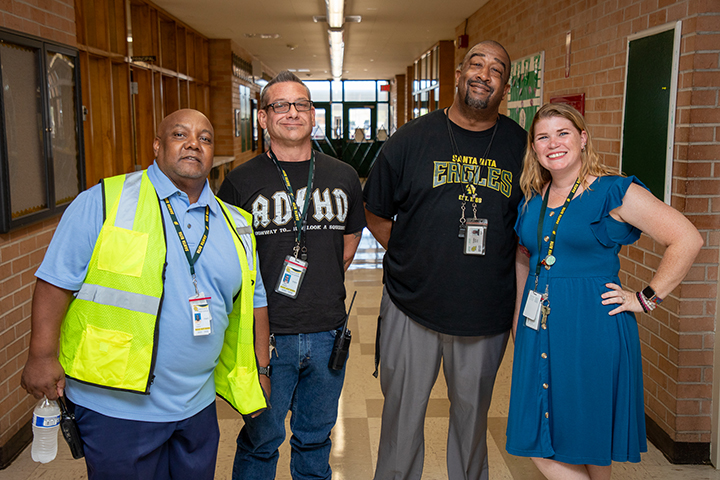 Four school employees smile in the hallway