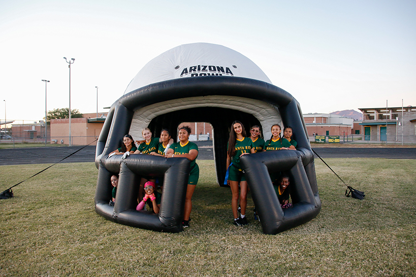 The girls flag football team poses inside the inflatable helmet