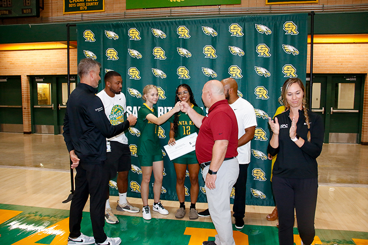 A teen girl fist bumps a man after the check presentation