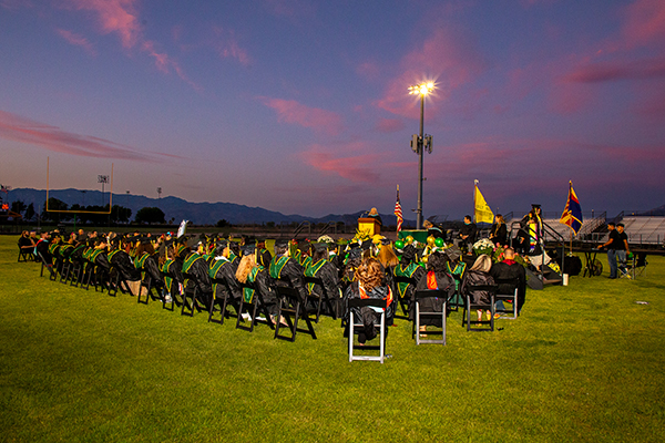 Graduates sit on the football field during the ceremony