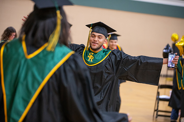 A graduate goes in to hug his friend