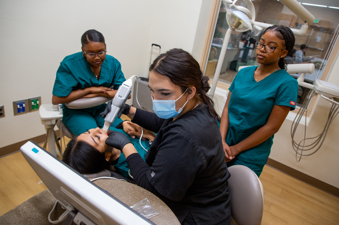 A dental tech works in a student's mouth to show fellow students how the scanner tool works